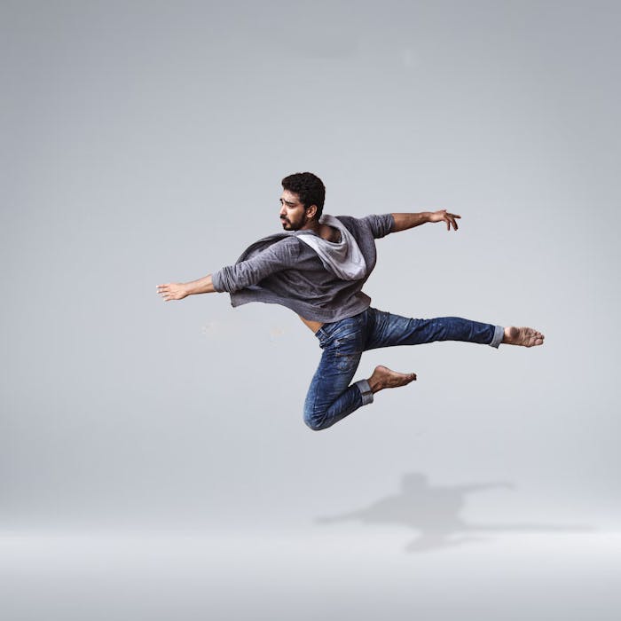 stats-img A male contemporary dancer in casual wear leaping gracefully in mid-air, showcasing agility and flexibility.