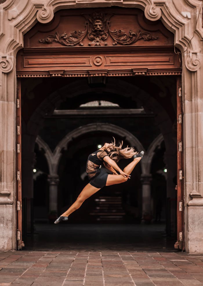 why-choose-us Ballet dancer performing a dramatic jump in a historic arch, Aguascalientes.