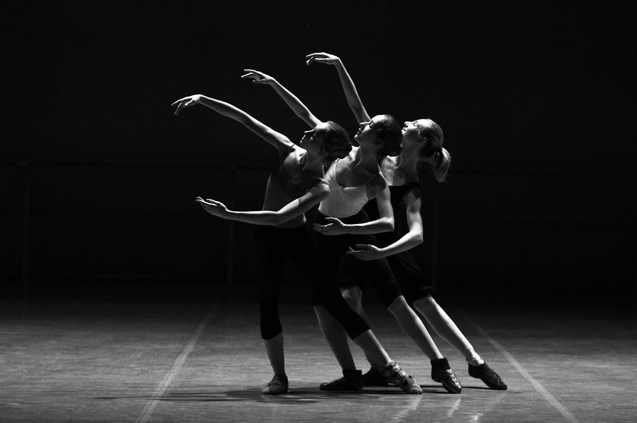 portfolio-06 Three female ballerinas perform a synchronized dance on stage in dramatic lighting.
